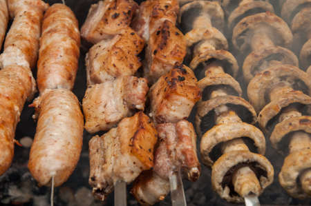 tasty pork ribs, sausages and field mushroom fried on skewers on a brazierの写真素材