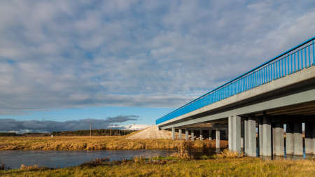 reinforced concrete bridge for transport through the narrow field river against the background of the beautiful cloudy sky. autumnの写真素材