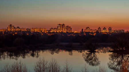 Beautiful dramatic evening city landscape. residential quarter behind the lake is illuminated by street lights and light from windowsの写真素材