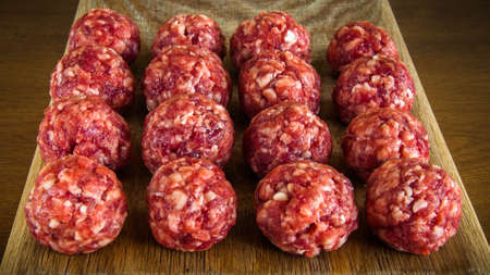 Even rows of meat balls from fresh ground beef on a wooden cutting boardの写真素材