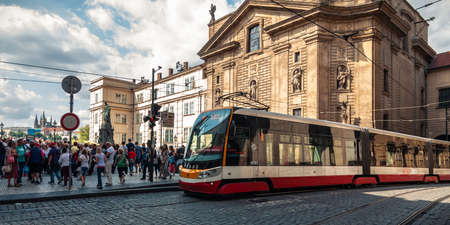 PRAGUE, CZECH REPUBLIC - Aug. 23, 2019: crowded street in the old district of Prague near the royal bridge with a modern tram, cobblestone road and many walking tourists on a nice summer dayのeditorial素材