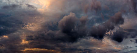 wide panoramic view of the dramatic sunset sky with heavy dark cumulus clouds and natural purple-orange lighting from the evening dawn. picturesque artistic backdrop for atmospheric design, decorationの写真素材