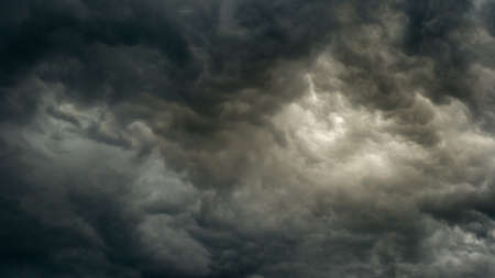 gray moody dramatic sky before the storm with unusual bizarre patterns of thick cumulus clouds and back light. panoramic view. Artistic picture for mystical design or decorationの写真素材