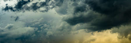 a wide panoramic view of the gloomy stormy dramatic sky with dark cumulus clouds and orange crimson from the bottom side. artistic creative picture for sad decoration or backgroundの写真素材