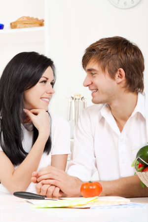 young lovely couple in their kitchen coocking happy smileの写真素材
