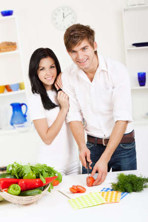 young lovely couple in their kitchen coocking happy smileの写真素材