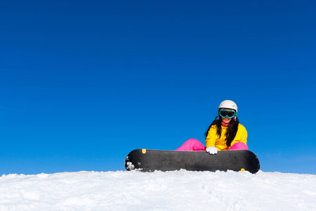 snowboarder woman sitting on snow mountain slopeの写真素材