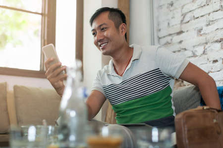 Asian Man Using Cell Phone Smile Sitting Cafeの写真素材