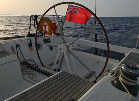 English sailing yacht flag Red Ensign United Kingdom civil vessel steering wheel sail boat