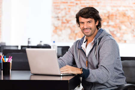 Man using laptop casual businessman smile sitting office desk working