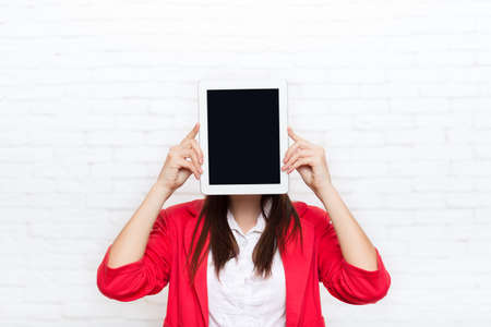 Businesswoman show tablet computer screen with empty copy space wear red jacket glasses happy smile business woman over office wallの写真素材