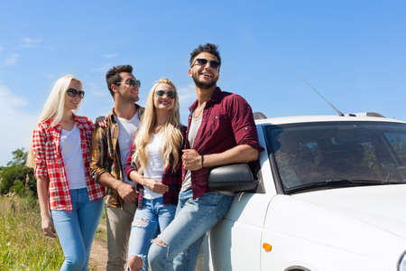 People group looking side copy space blue sky standing near car outdoor countryside two couple summer day holiday tripの写真素材