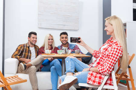 People taking selfie friends pictures drinking coffee shop with barista sitting table mix race men hold smart phone woman happy smileの写真素材