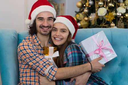 Christmas Holiday Happy Couple Wear New Year Santa Hat Cap, Man And Woman Embracing Holding Present...
