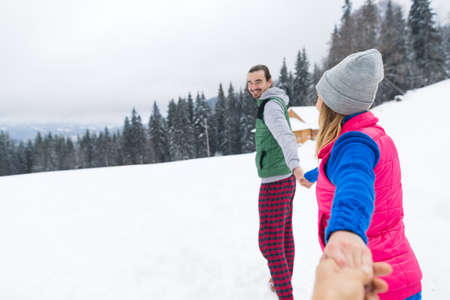 Young Couple Snowy Village Wooden Country House Man And Woman Winter Snow Resort Cottage Holiday Vacationの写真素材