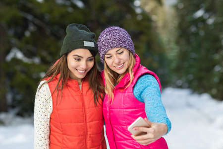 Girl Hold Smart Phone Camera Taking Selfie Photo Snow Forest Young Woman Couple Outdoor Winter Pine...