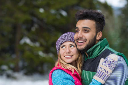 Young Mix Race Couple Embrace Snow Forest Outdoor Winter Walk Pine Woodsの写真素材