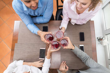 Young Business People Group Sitting At Cafe Table Toasting, Hold Wine Glasses, Friends Cheers Top...