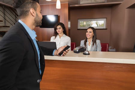 Business Man Arrive To Hotel Check In With Cell Phone Woman Receptionist Registration At Reception Counter