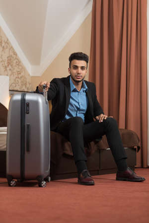 Business Man Sitting At Bed In Room Seriuos Upset Latin Businessman With Luggage Suitcase Arriving...