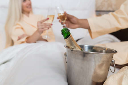 Young Couple Lying In Hotel Bed Drink Champange, Happy Man And Woman Lovers In Bedroomの写真素材