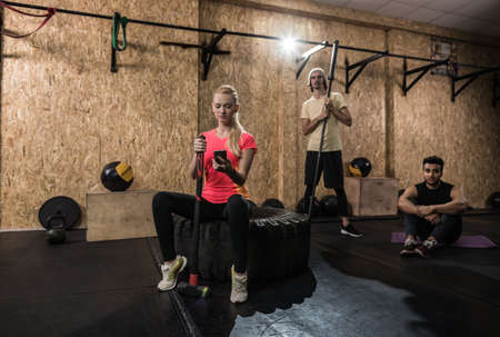 Sport Fitness People Group Crossfit Training Equipment, Serious Young Healthy Man And Woman Gym Interior Doing Exercisesの写真素材