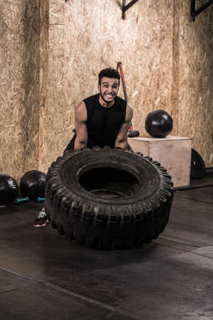 Sport Fitness Man Flipping Wheel Tire Crossfit Training, Young Healthy Guy Gym Interiorの写真素材