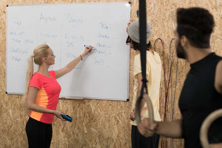 Sport Fitness People Group Write Results After Crossfit Training On Board, Young Healthy Man And Woman Gym Interiorの写真素材