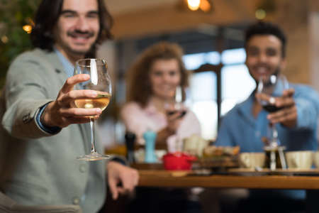 Young Business People Group Drink Wine Sitting Restaurant Table, Friends Hold Glasses Toasting...