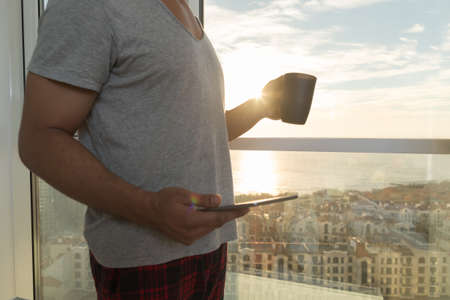 Hispanic Man Using Cell Smart Phone Modern Apartment Big Panoramic Window Sea View, Young Guy...