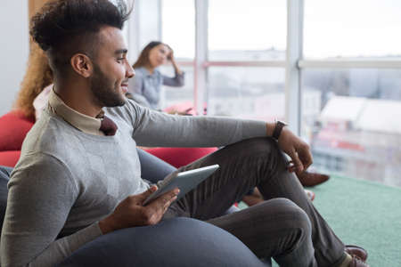 Hispanic Businessman In Coworking Center Business Team Coworkers Using Tablet Computers Sitting in front Panoramic Window Modern Officeの写真素材