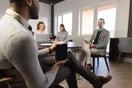 Hispanic Business Man Holding Blank Tablet Businesspeople Group In Coworking Center Diverse Mix Race Team Coworkers Meeting Modern Officeの写真素材