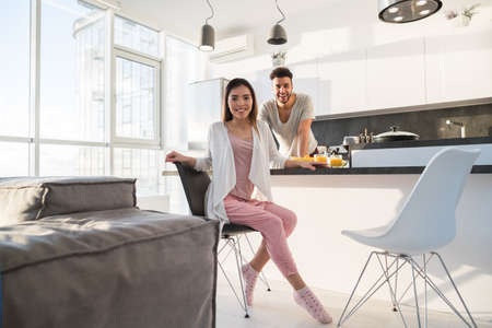 Young Couple Having Breakfast, Asian Woman Hispanic Man Cooking Food Kitchen Modern Apartment Interiorの写真素材