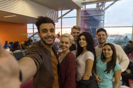 Young People Group In Airport Lounge Waiting Departure Happy Smile Mix Race Friends Taking Selfie Photo Flightの写真素材