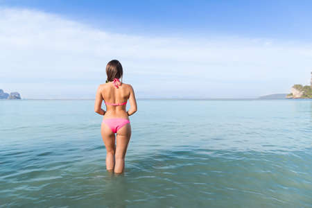 Attractive Young Caucasian Woman In Swimsuit On Beach Back Rear View, Girl Blue Sea Water Holiday Summer Vacationの写真素材