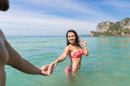 Couple On Beach Summer Vacation, Young People In Water, Woman Holding Man Hand Sea Ocean Holiday Travelの写真素材