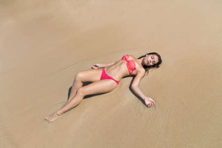 Attractive Young Caucasian Woman In Swimsuit Lying On Beach Top View, Girl Wet Sand Sea Ocean Holiday Summer Vacationの写真素材