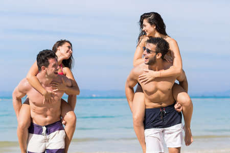 Two Couple On Beach Summer Vacation, Young People Happy Smiling, Man Carry Woman Sea Ocean Holiday Travelの写真素材