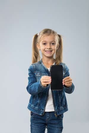 Little Teenage Girl Show Cell Smart Phone Screen With Empty Copy Space, Small Kid Happy Smiling Child Isolated Over Gray Backgroundの写真素材