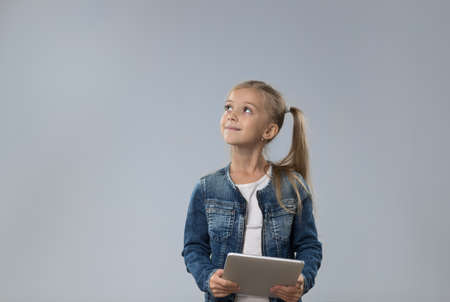 Little Teenage Girl Using Tablet Computer, Small Child Looking Up To Copy Space Isolated Over Gray...
