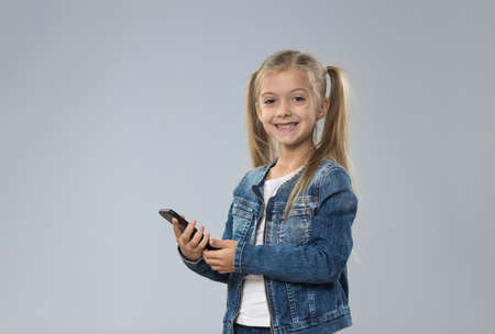 Little Teenage Girl Using Cell Smart Phone, Small Kid Happy Smiling Child Isolated Over Gray Backgroundの写真素材