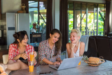 Three Girls Sitting At Table Use Laptop Computer Happy Smiling, Young Woman Friends Together Communication Conceptの写真素材