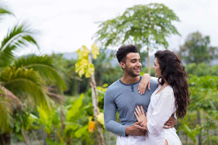 Happy Latin Man Embracing Woman, Young Couple Over Green Tropical Rain Forest Landscape Smiling In Cameraの写真素材