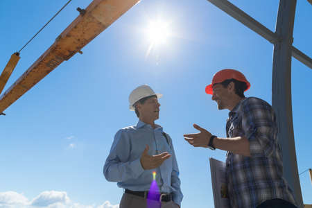 Builder And Business Man Discussing Project Meeting Outdoors On Buiding Constuction Site Two Engineer Talkingの写真素材