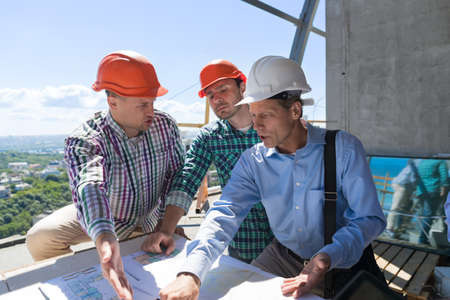 Team Of Builders Working With Blueprint On Site Architect Explain Construction Plan To Team Og...