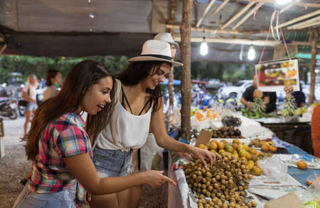Two Woman Choosing Exotic Fruits On Tropical Street Market Young Female Tourists Buying Fresh Food On Asian Bazaarの写真素材