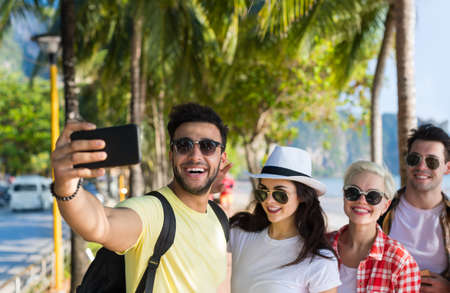 Young People Group On Beach Taking Selfie Photo On Cell Smart Phone Summer Vacation, Happy Smiling Friends Sea Holiday Ocean Travelの写真素材