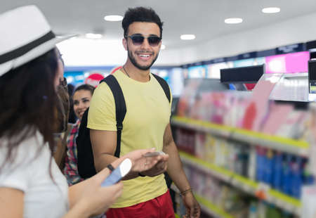 Young Couple In Supermarket Choosing Products Happy Smiling Man And Woman Buying Cosmetics Shop Interiorの写真素材
