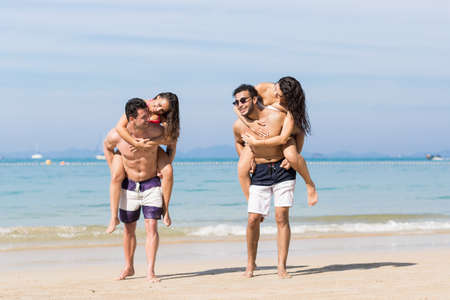 Two Couple On Beach Summer Vacation, Young People Happy Smiling, Man Carry Woman Sea Ocean Holiday Travelの写真素材