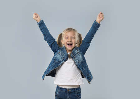 Beautiful Little Girl Excited Hold Hands Up Happy Smiling Wear Jeans Coat Isolated Over Gray Backgroundの写真素材